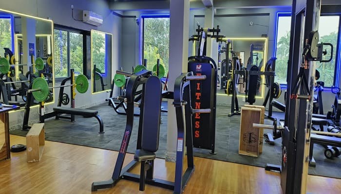 Weight-training area with plate-loaded machines and mirrors at G2 Fitness Club